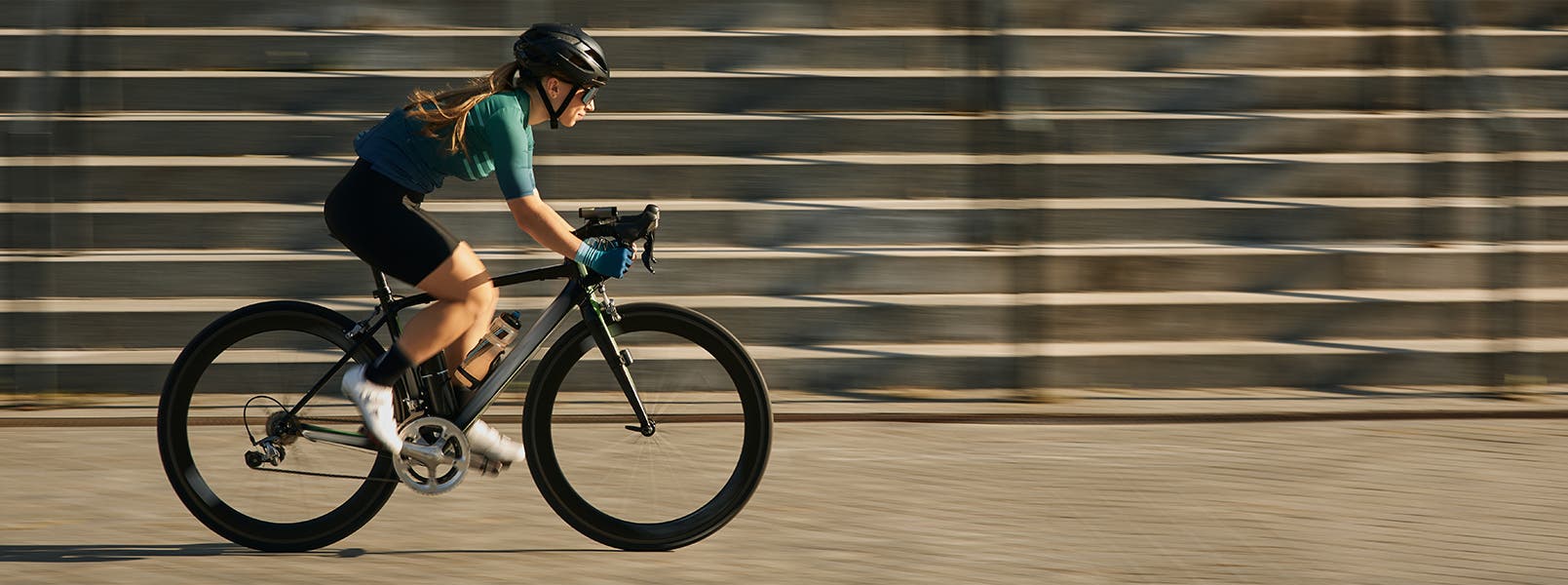 A woman cycling in sleek gear and a helmet.