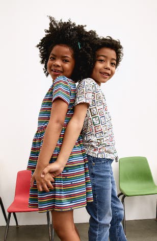 Child wearing a striped dress. Child wearing a patterned T-shirt and jeans.