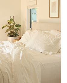 A bed made with white linens and duvet.