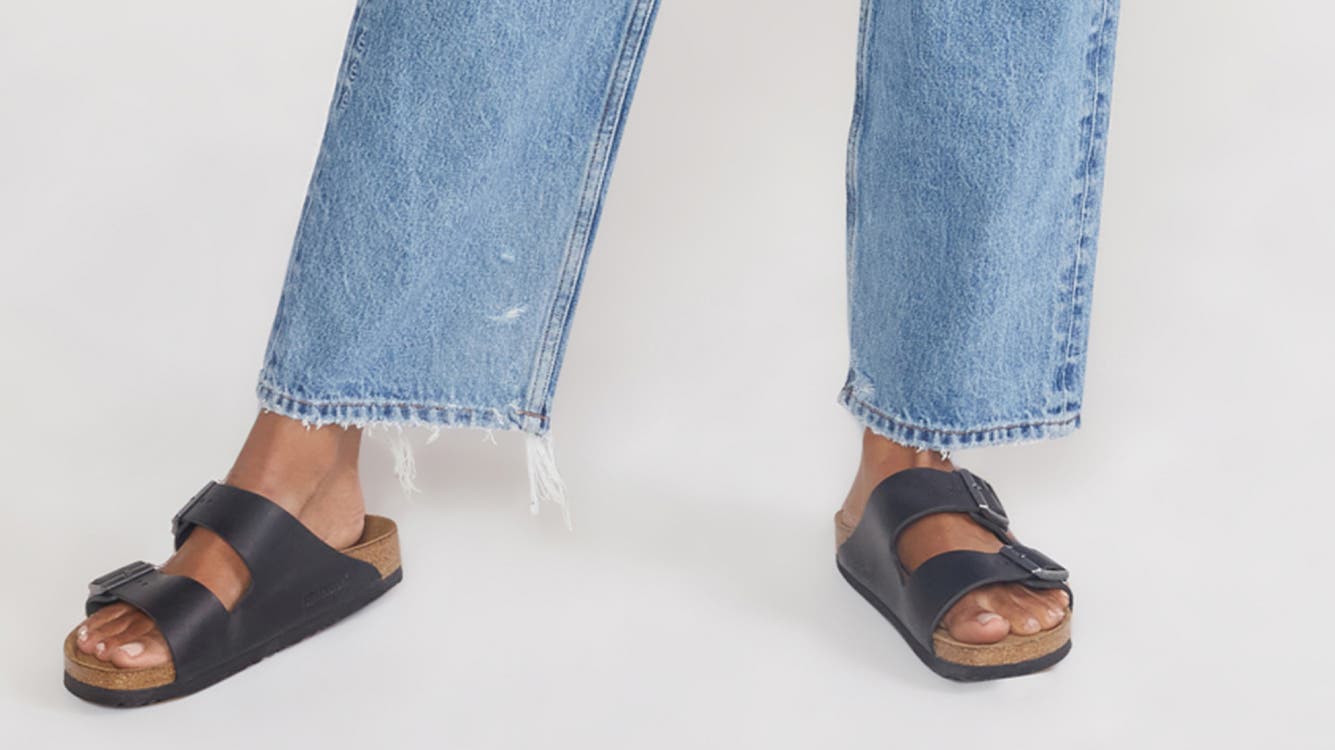 A woman wearing blue jeans with black sandals.