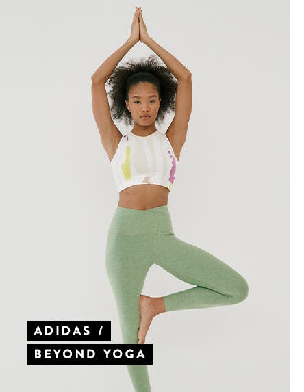 Woman wearing a white active crop top and green high-waist yoga leggings.