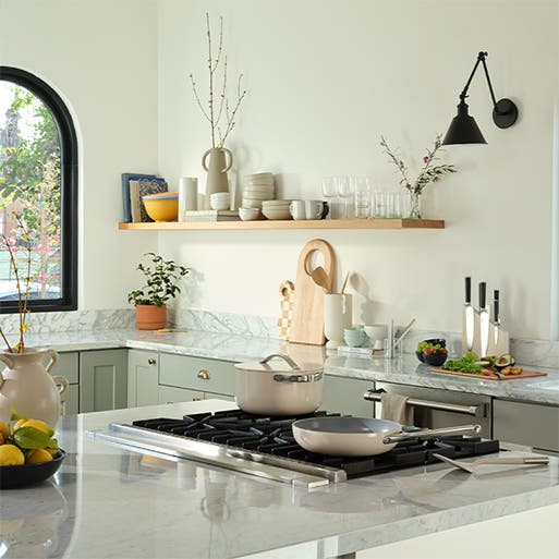 A soothing kitchen with neutral cookware and dishes.