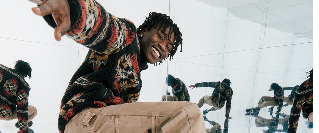Make it adventurous. Our holiday picks. A man in a patterned sweater, cargo pants and hiking boots.