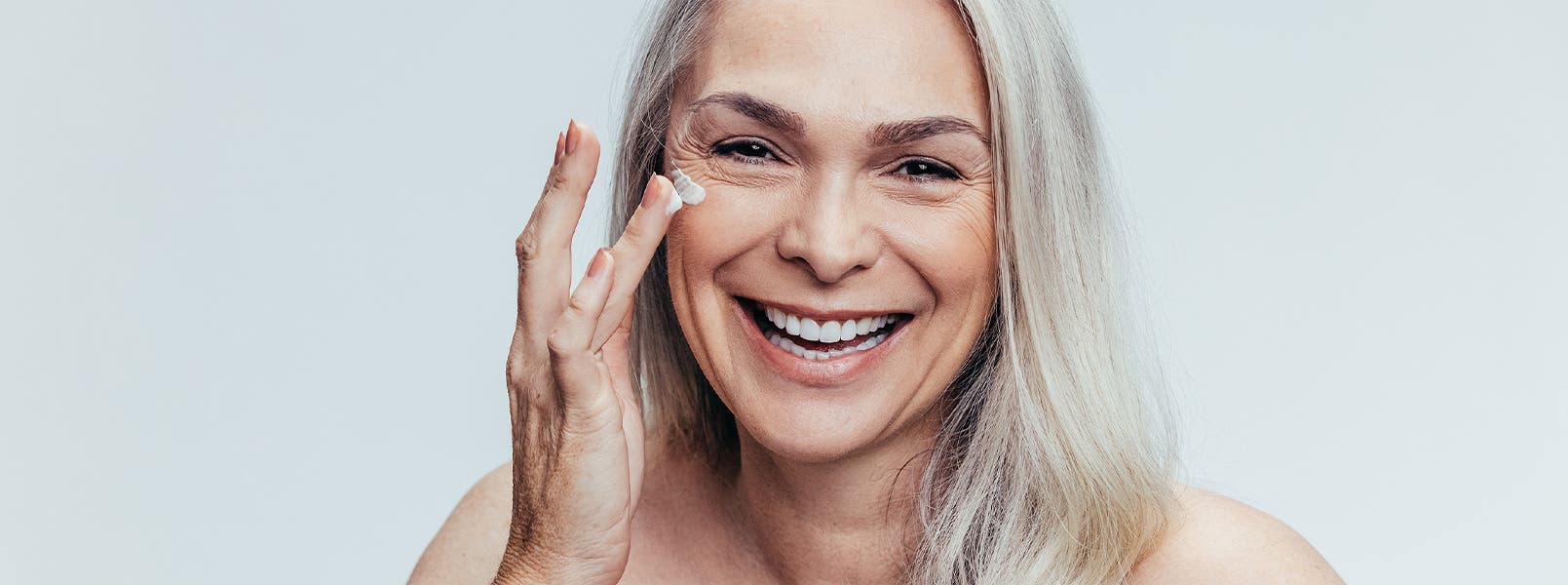 An older woman applying eye cream.