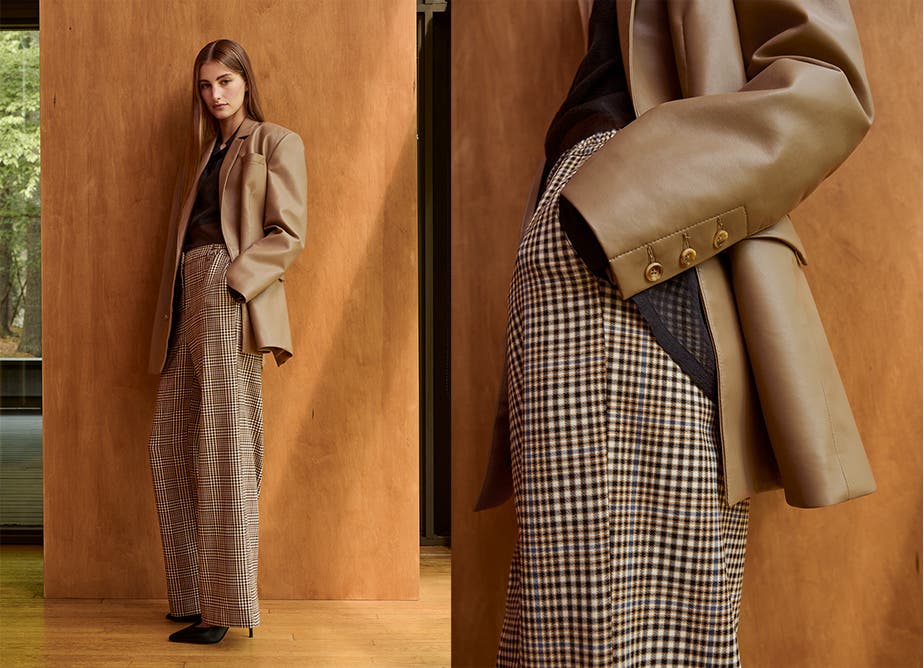 A woman in a brown leather jacket and checked wide-leg pants.