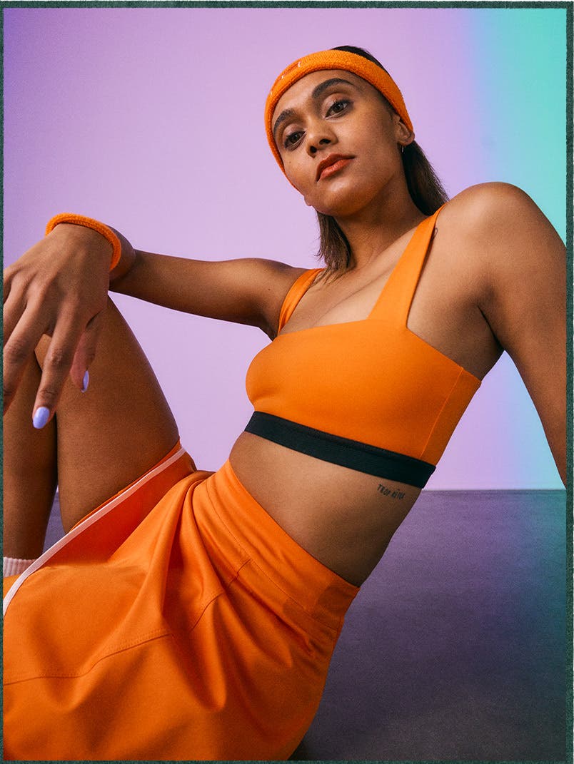 Woman in an orange activewear set from Full Court Sport.