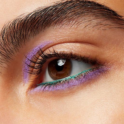 A woman wearing purple and green eyeliner.