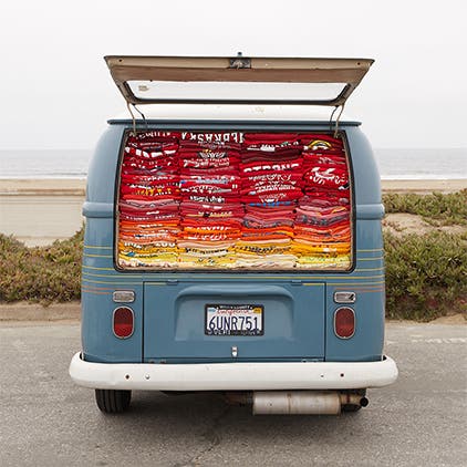 The trunk of Marine Layer's VW bus open to show stacks of T-shirts inside.