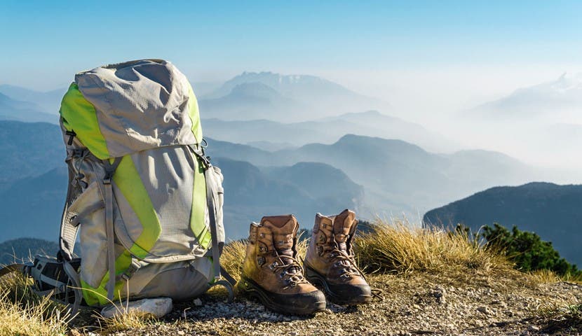Hiking equipment with backpack and boots on top of mountain