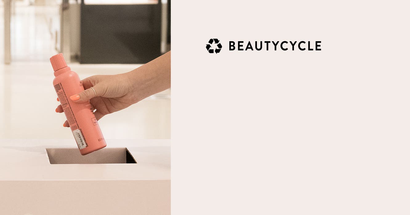 An empty shampoo bottle being placed in a BEAUTYCYCLE bin.