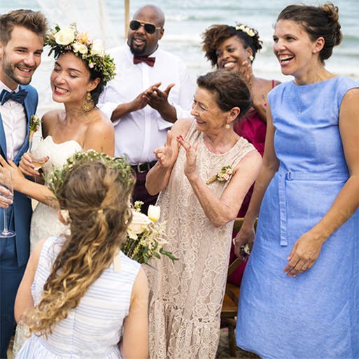 A couple surrounded by family and friends at their beach wedding.