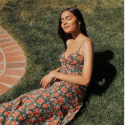 A woman wearing a summer dress laying on the grass.