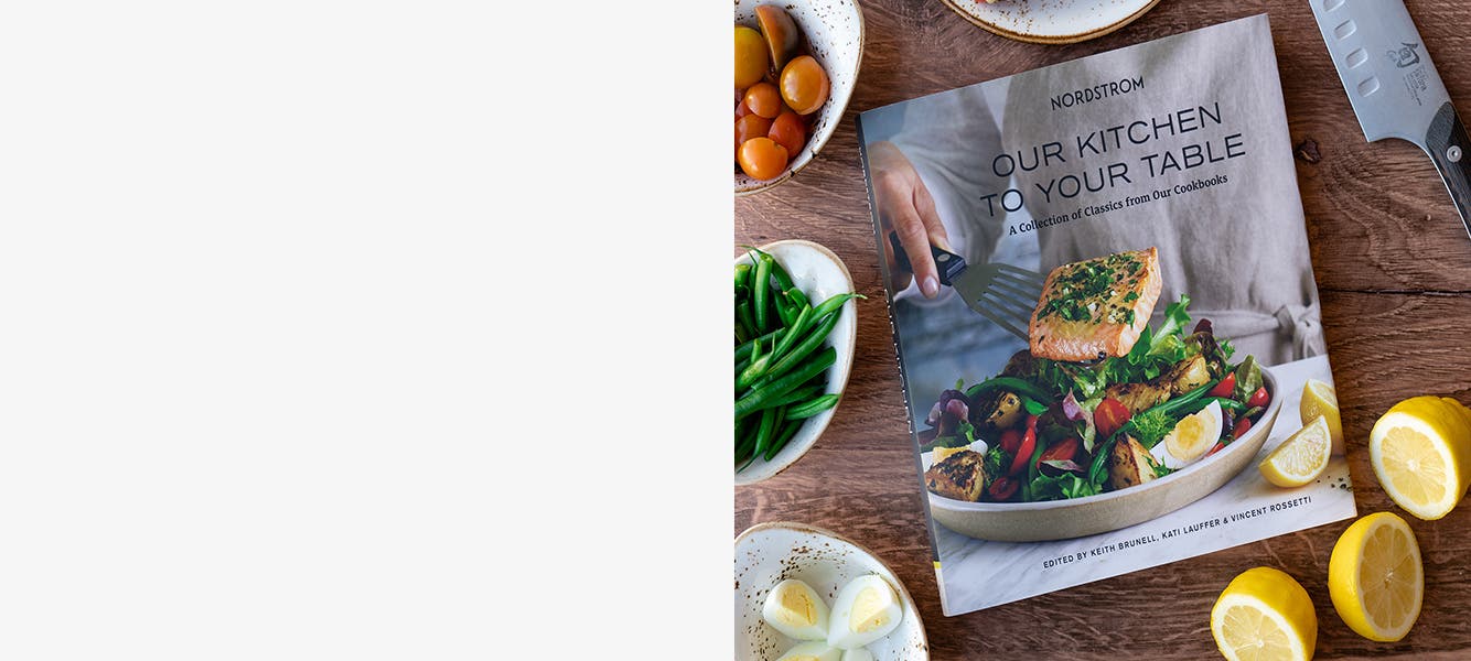 Our Kitchen to Your Table cookbook on a table with ingredients for a salad niçoise.