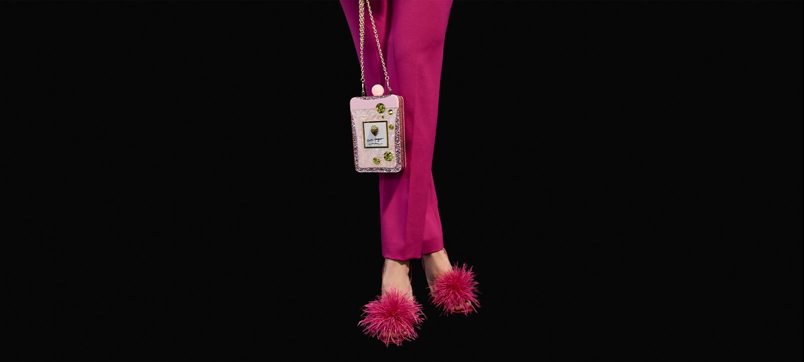 Model wearing magenta pants, shoes with magenta feathers and pink handbag.