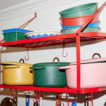 A wall rack holding colorful cookpots and bakeware.