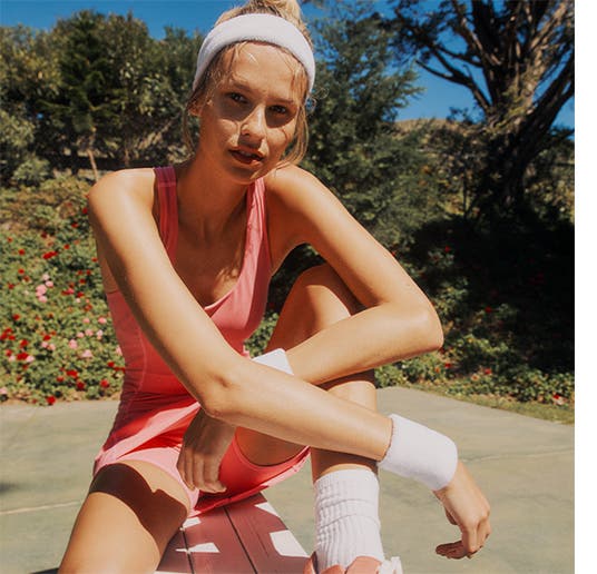 Woman in pink tennis gear with a white headband, wrist band and socks.