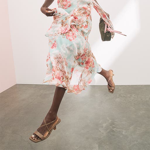 A woman wearing high-heel sandals with a floral-print dress.