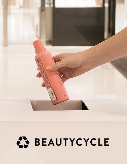 An empty shampoo bottle being placed in a BEAUTYCYCLE bin.