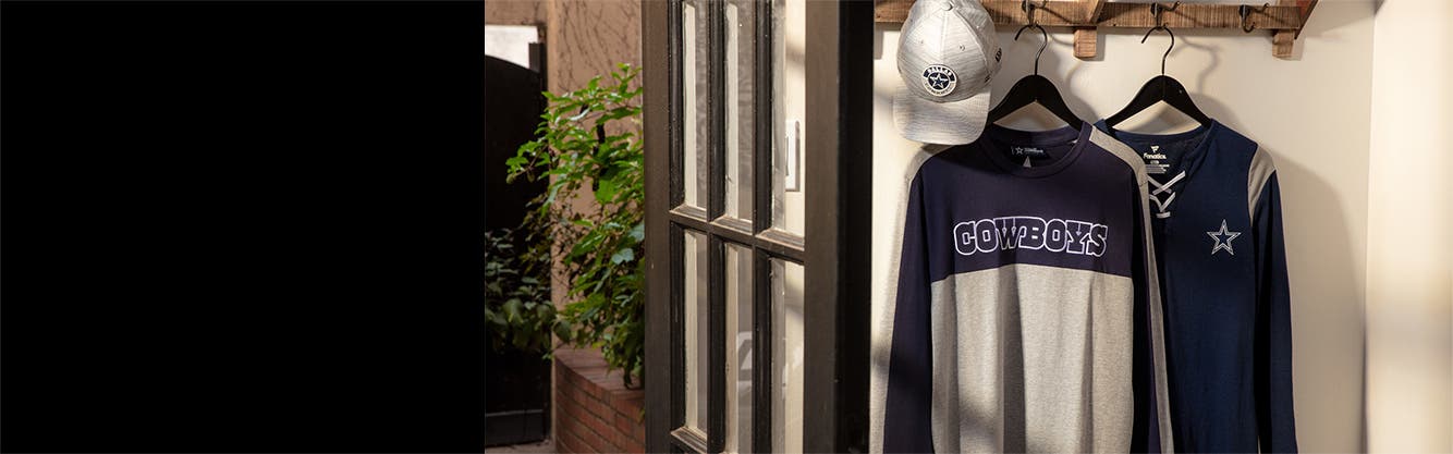 Gear up for game day: a hat and two long-sleeve Dallas Cowboys shirts hanging on a clothing rack; 5 hats featuring logos of different MLB teams; an Oklahoma cap and sweatshirt.