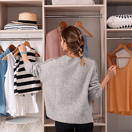 A woman looks at clothing in a closet.
