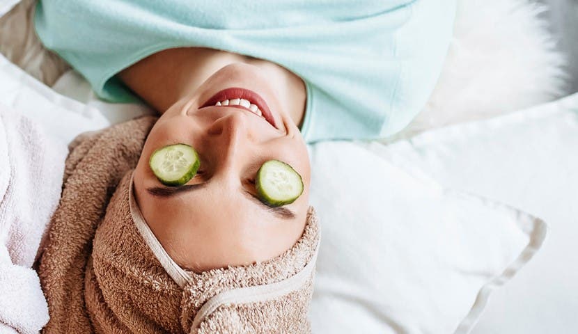 girl smiling with cucumbers over eyes