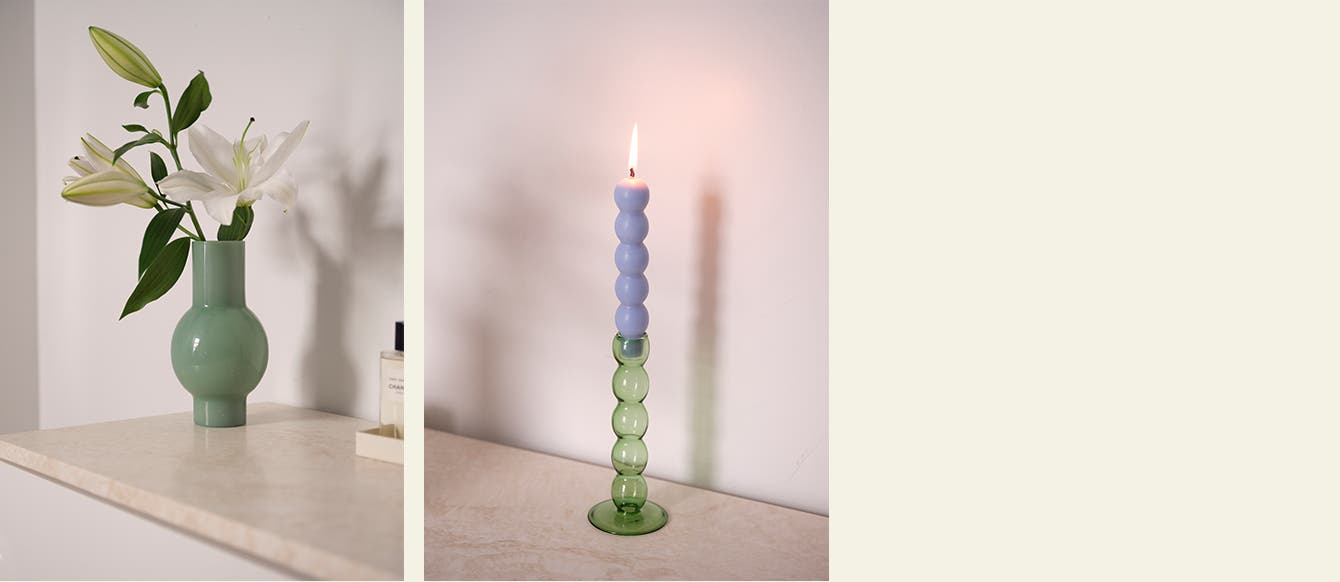 A green vase. A glass candle holder and sculptural candle.