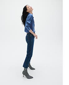 A woman wearing a blue top with jeans and stiletto boots.