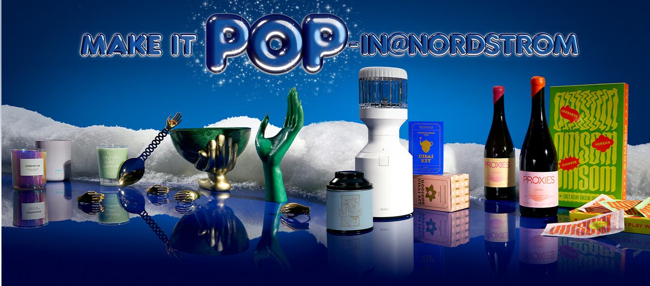 Make It Pop-In@Nordstrom. A selection of gifts in the snow including a green bowl and serving spoon adorned with a golden hand, a hand-shaped candle and napkin rings, a scented candle, personal blender and chai kits.