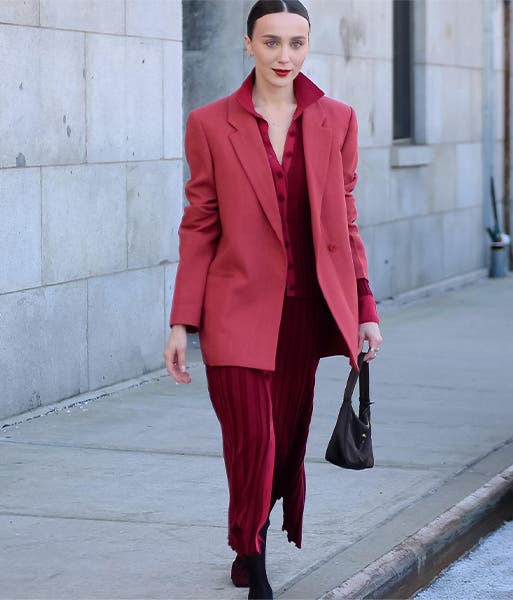 A woman wearing a burgundy dress and complementary merlot-colored blazer.