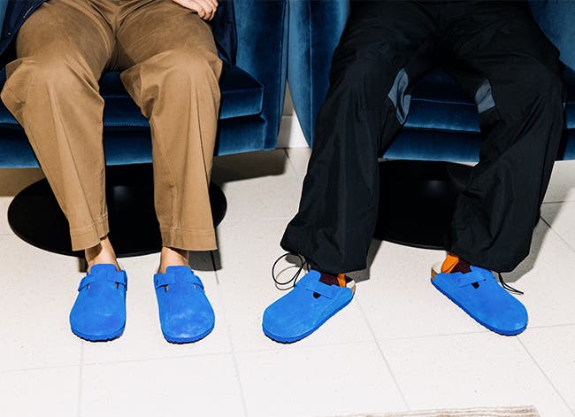 Two men seated, wearing the newest color of the Birkenstock Boston clog in electric blue.