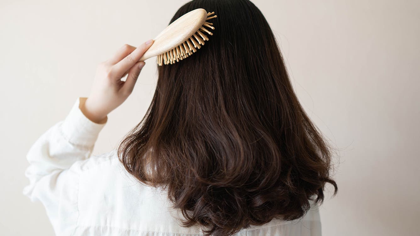 A woman brushes her hair.