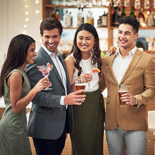 A group of professionally dressed women and men hanging out at a bar.
