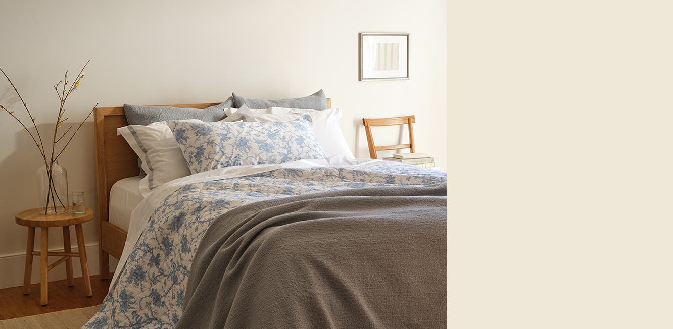 A bed set with blue, grey and white linens.
