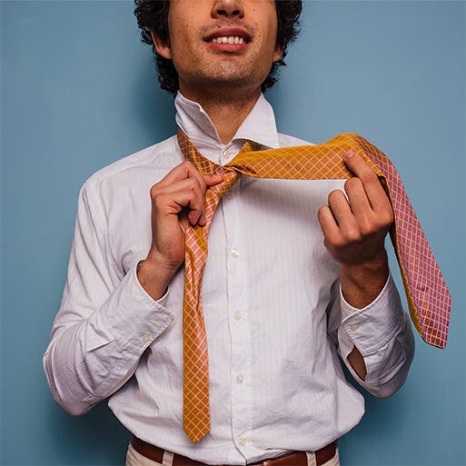 A man in the process of tying a tie.