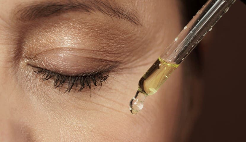 woman with eyes closed applying face serum