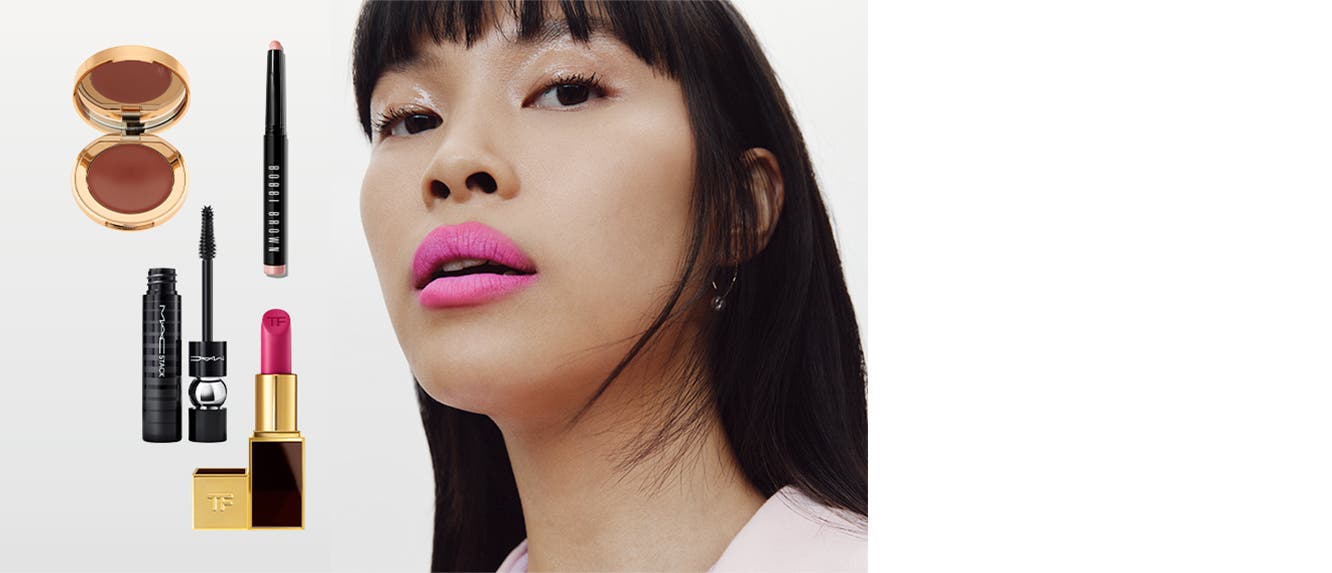 Model wearing bright pink lipstick. A cream blush, pink lipstick, pink eyeshadow stick and mascara tube.