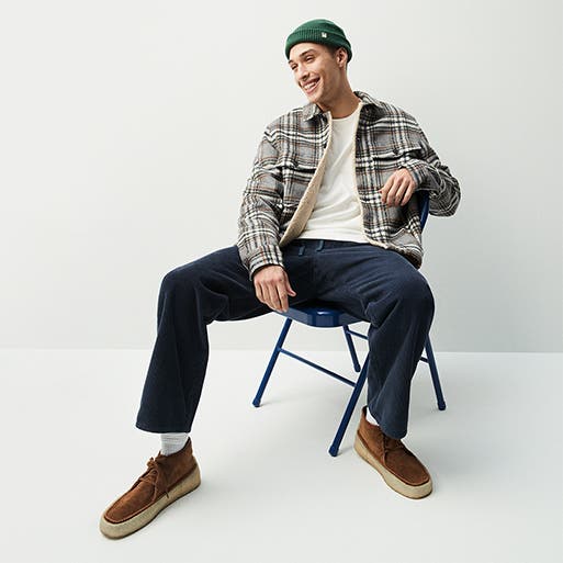 A man in a casual outfit including a beanie, flannel shirt and boots.