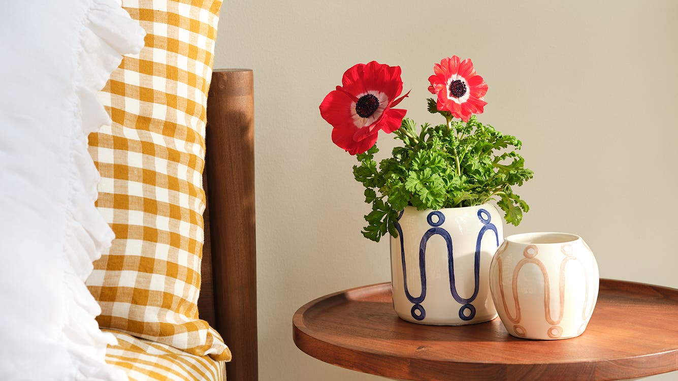 Two vases with abstract designs placed on a nightstand next to a bed.