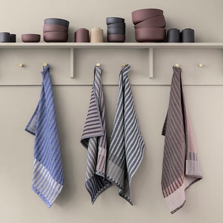 Striped tea towels hanging on wall pegs.