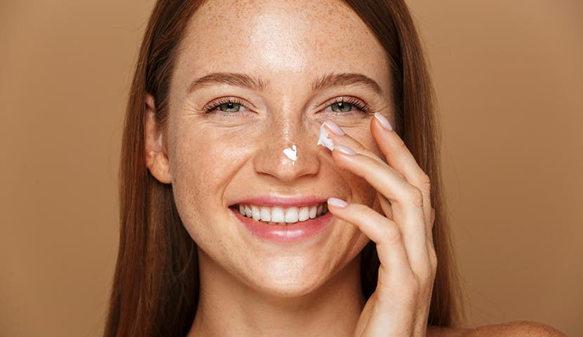 woman smiling adding moisturizer to face
