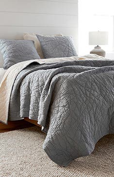 A grey coverlet and shams.