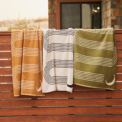 Green, rust and stone colored bath towels with a fun pattern.