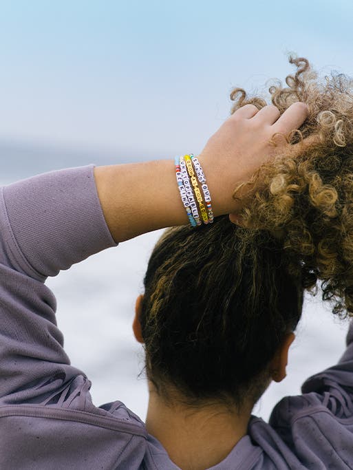 Closeup of Laurie Hernandez's wrist wearing bracelets from her Little Words Project collection.