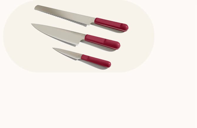 Chef's knife, serrated knife and paring knife with rose-colored handles.