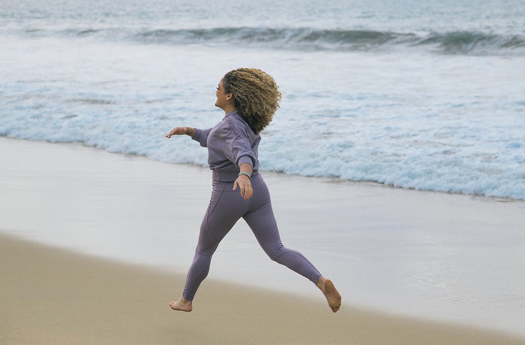 Laurie Hernandez running on a beach by the water.