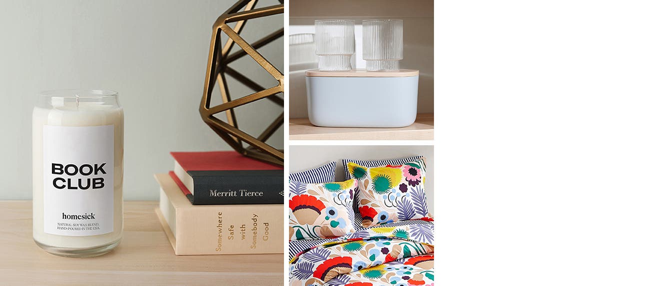 A homesick Book Club candle, two glasses on top of a bin with lid, Marimekko bedding.
