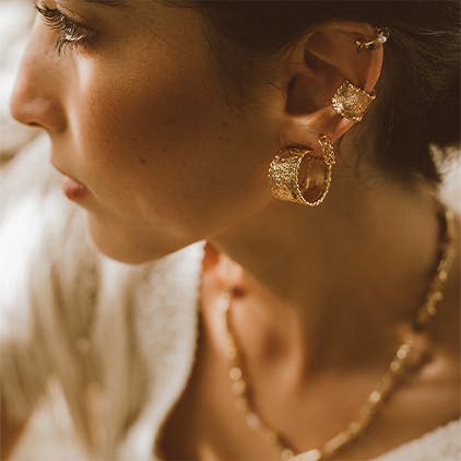 A woman wearing Crisobela earrings and a necklace.