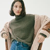 A woman wearing a jacket and sweater.