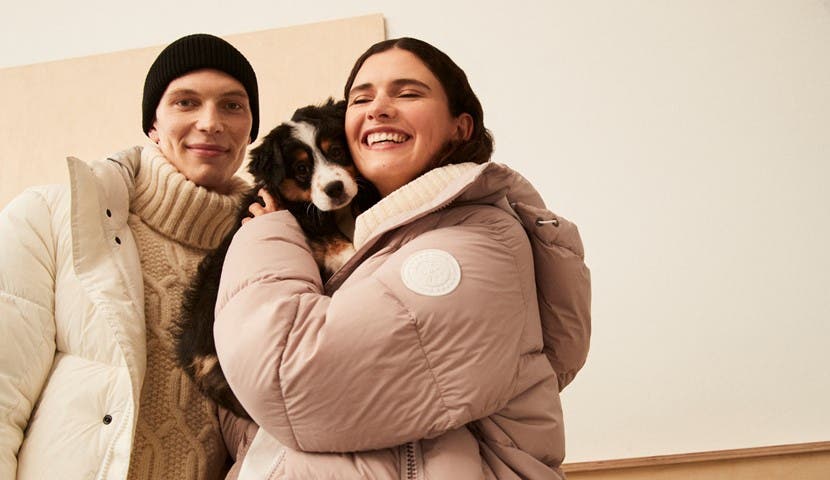 woman and man in puffer jackets holding a puppy
