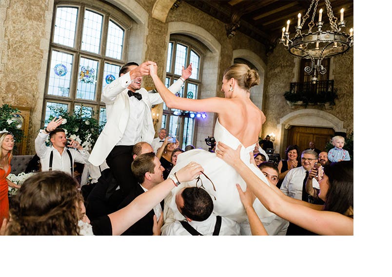 Newlyweds Holly and Abraham are lifted above the crowd of their wedding reception.